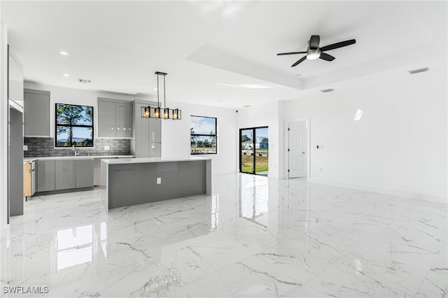 kitchen with decorative light fixtures, a center island, gray cabinets, and plenty of natural light