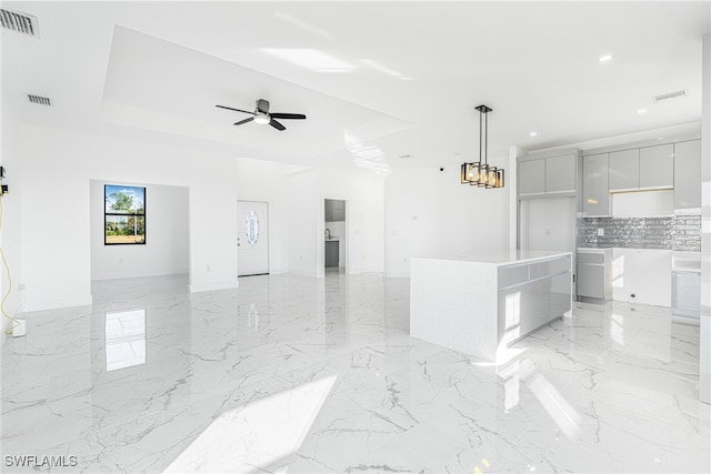 kitchen with backsplash, ceiling fan, decorative light fixtures, a kitchen island, and white cabinetry