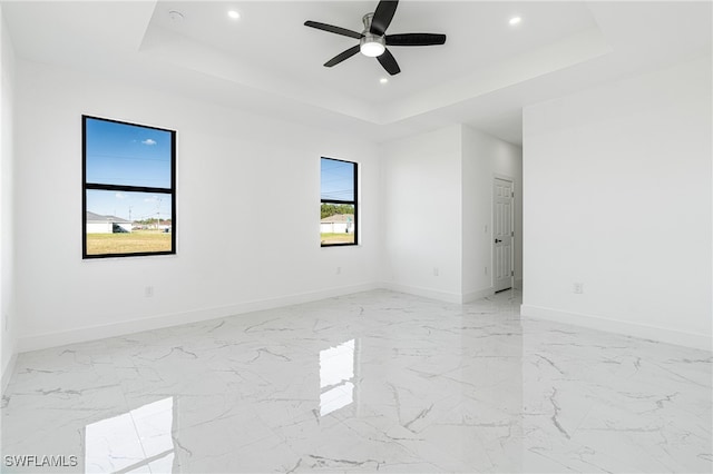 unfurnished room featuring ceiling fan and a tray ceiling