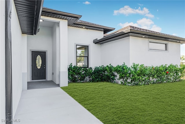 doorway to property featuring a lawn