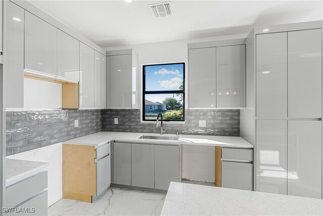 kitchen with decorative backsplash, gray cabinets, and sink