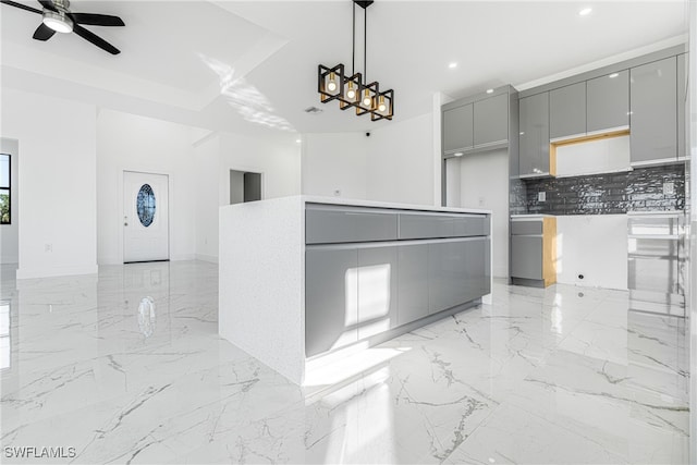 kitchen with tasteful backsplash, gray cabinets, a center island, and pendant lighting