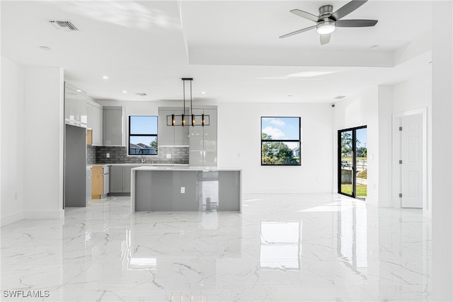 kitchen with ceiling fan, a center island, hanging light fixtures, gray cabinets, and decorative backsplash