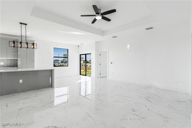 unfurnished living room with a tray ceiling and ceiling fan