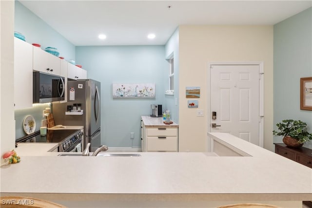 kitchen with stainless steel appliances, kitchen peninsula, sink, and white cabinets