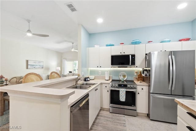 kitchen with appliances with stainless steel finishes, white cabinets, ceiling fan, and kitchen peninsula