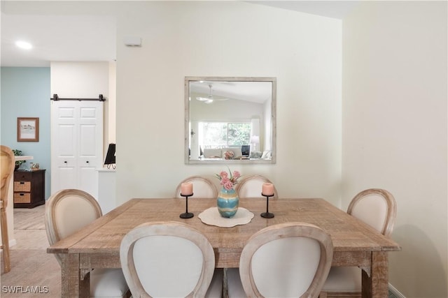 dining room featuring a barn door and vaulted ceiling