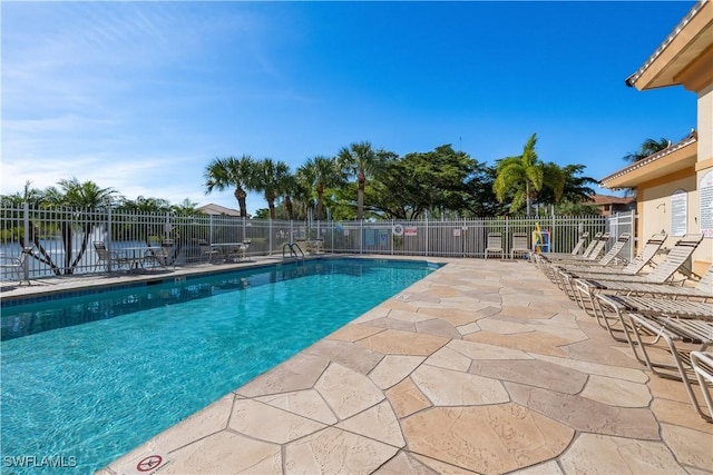 view of swimming pool featuring a water view and a patio area