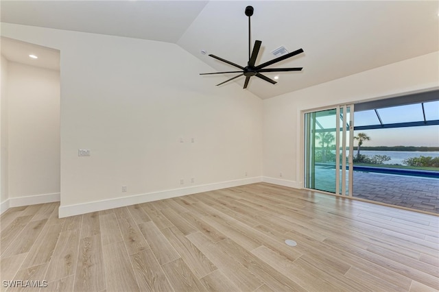 spare room with ceiling fan, a water view, lofted ceiling, and light wood-type flooring