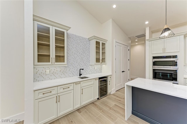 kitchen featuring hanging light fixtures, wine cooler, double oven, tasteful backsplash, and light stone counters