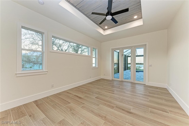 empty room featuring a tray ceiling, ceiling fan, and light hardwood / wood-style floors