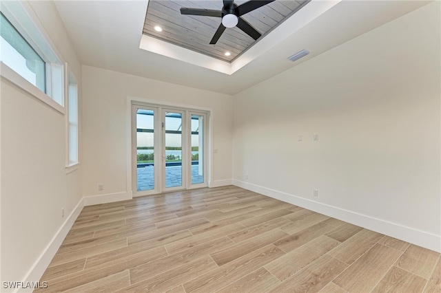 spare room with a tray ceiling, light hardwood / wood-style flooring, and ceiling fan