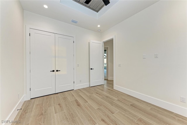 unfurnished bedroom featuring ceiling fan, a closet, and light hardwood / wood-style floors