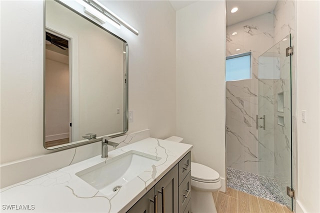 bathroom with hardwood / wood-style floors, vanity, an enclosed shower, and toilet