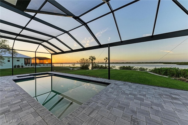 pool at dusk with a lanai, a patio area, a water view, and a yard