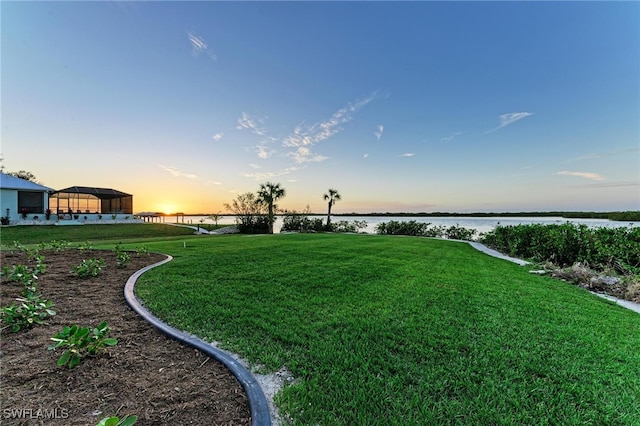 yard at dusk featuring a water view