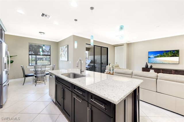 kitchen featuring light stone counters, stainless steel appliances, sink, a center island with sink, and hanging light fixtures