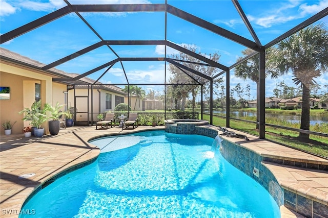 view of pool with an in ground hot tub, pool water feature, a water view, glass enclosure, and a patio