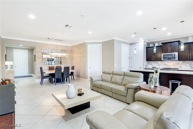 tiled living room with crown molding and a chandelier