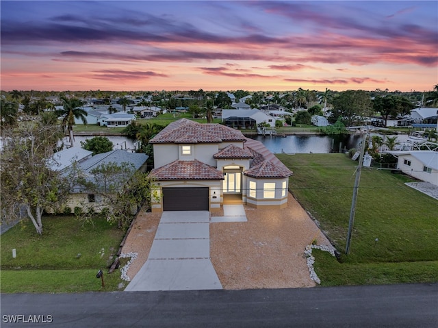 view of front facade with a water view, a garage, and a lawn