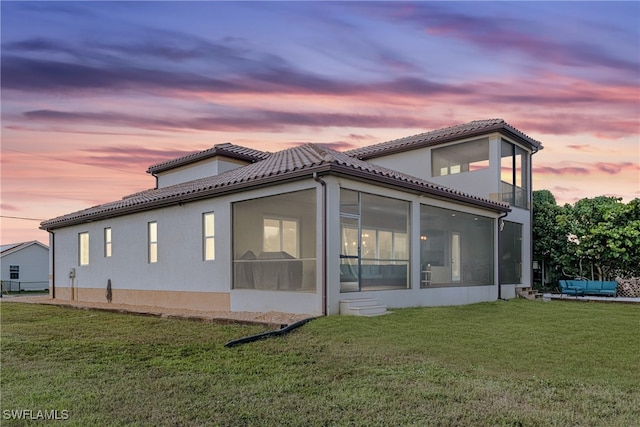 property exterior at dusk featuring a yard and a sunroom