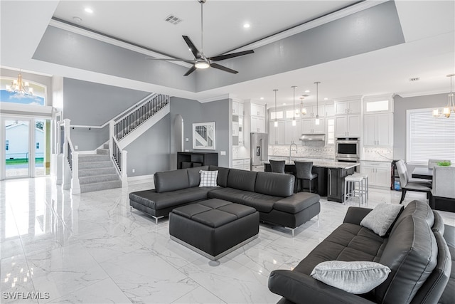 living room featuring ceiling fan with notable chandelier, sink, a towering ceiling, and crown molding