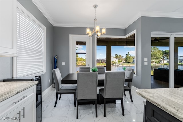 dining room featuring ornamental molding, a water view, and a notable chandelier