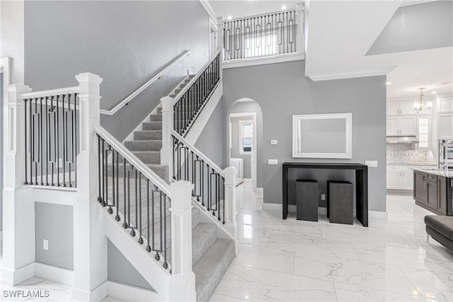 stairway featuring a high ceiling and a notable chandelier