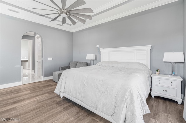 bedroom featuring dark hardwood / wood-style flooring, ceiling fan, ornamental molding, and connected bathroom