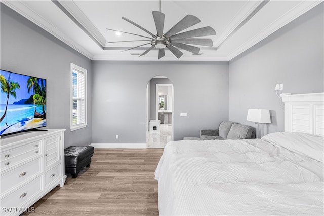 bedroom with a raised ceiling, ceiling fan, light wood-type flooring, and ornamental molding