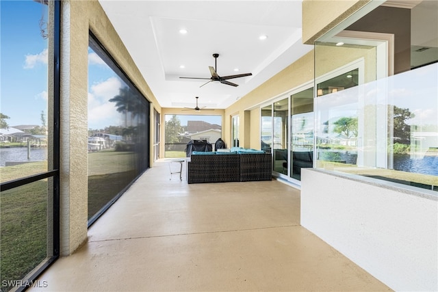 sunroom with a water view, ceiling fan, and a tray ceiling