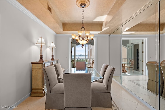 tiled dining space featuring a notable chandelier, a raised ceiling, ornamental molding, and a textured ceiling