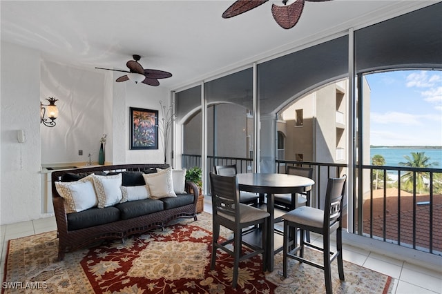 living room featuring light tile patterned floors, a water view, expansive windows, and ceiling fan