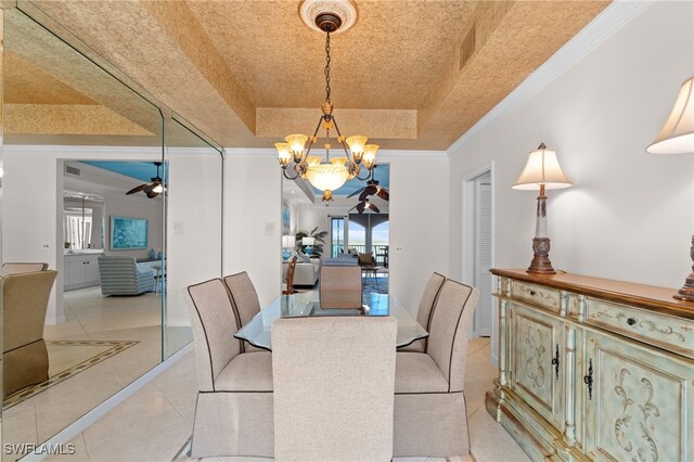 dining area featuring a raised ceiling, crown molding, light tile patterned floors, and ceiling fan with notable chandelier