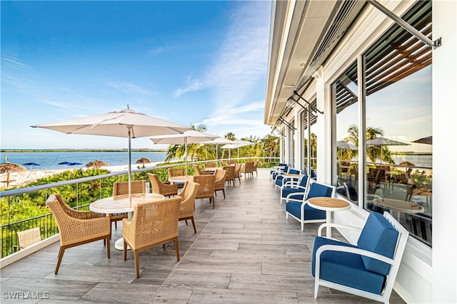 view of patio featuring a water view, a beach view, and a balcony