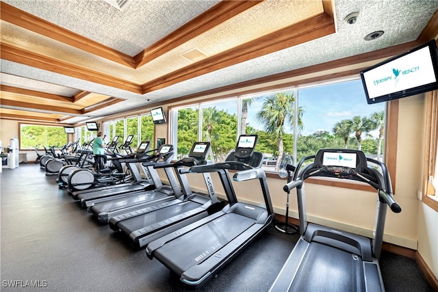 exercise room with a textured ceiling, a tray ceiling, and crown molding