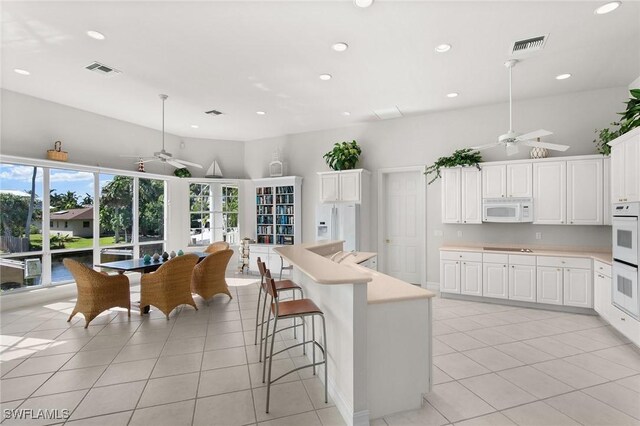 kitchen featuring a center island, light tile patterned floors, decorative light fixtures, white appliances, and white cabinets