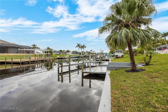 view of dock with a lawn and a water view