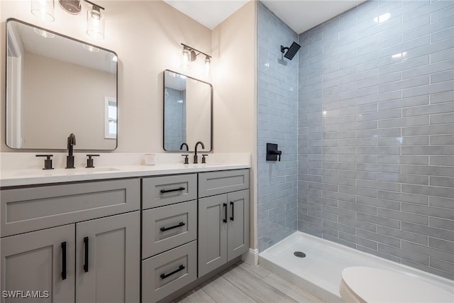 bathroom with tiled shower, vanity, and toilet