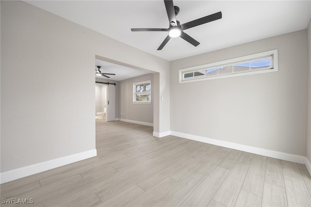 spare room featuring a barn door and light hardwood / wood-style floors