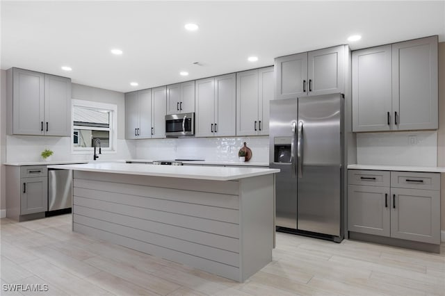 kitchen with appliances with stainless steel finishes, gray cabinets, and a kitchen island