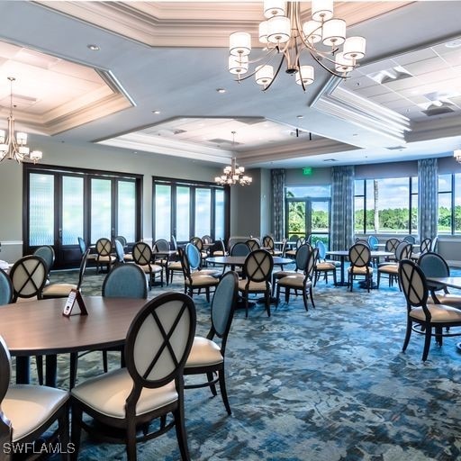 dining room with carpet, a raised ceiling, crown molding, and a chandelier