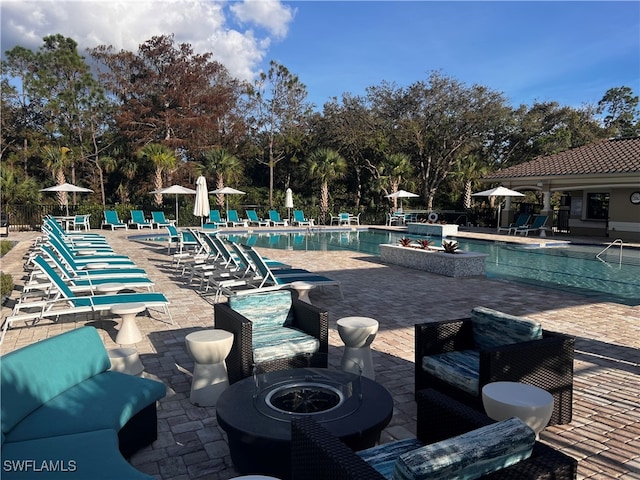 view of pool featuring a patio area and an outdoor living space with a fire pit