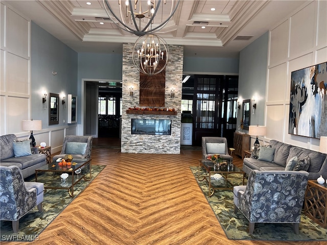 living room featuring ornamental molding, coffered ceiling, a notable chandelier, a fireplace, and a high ceiling