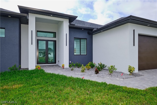 entrance to property with french doors, a yard, and a garage