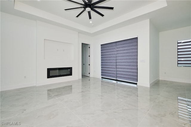 unfurnished living room featuring a raised ceiling and ceiling fan