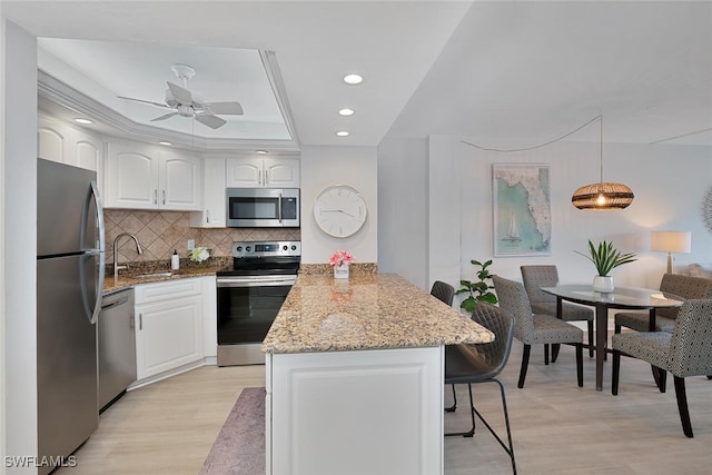 kitchen with white cabinetry, sink, hanging light fixtures, and appliances with stainless steel finishes