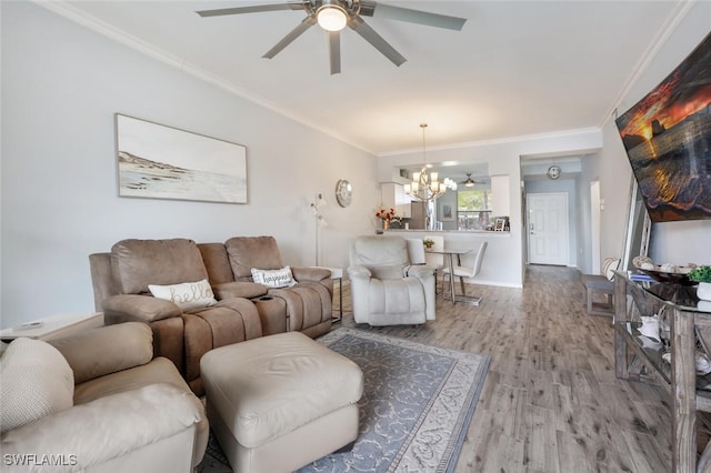 living room with ceiling fan with notable chandelier, light hardwood / wood-style floors, and ornamental molding