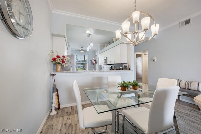 dining area featuring ceiling fan with notable chandelier, light wood-type flooring, and ornamental molding