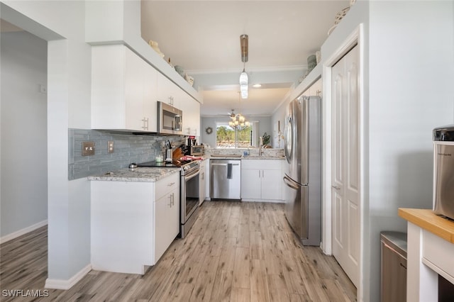 kitchen featuring white cabinets, light wood-type flooring, ornamental molding, appliances with stainless steel finishes, and decorative light fixtures